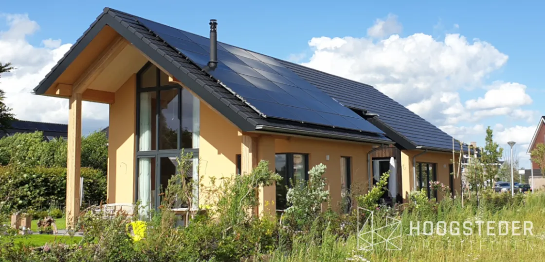 Woning met okerkleurige kalkhennep gevel, zonnepanelen op het dak en een wilde tuin