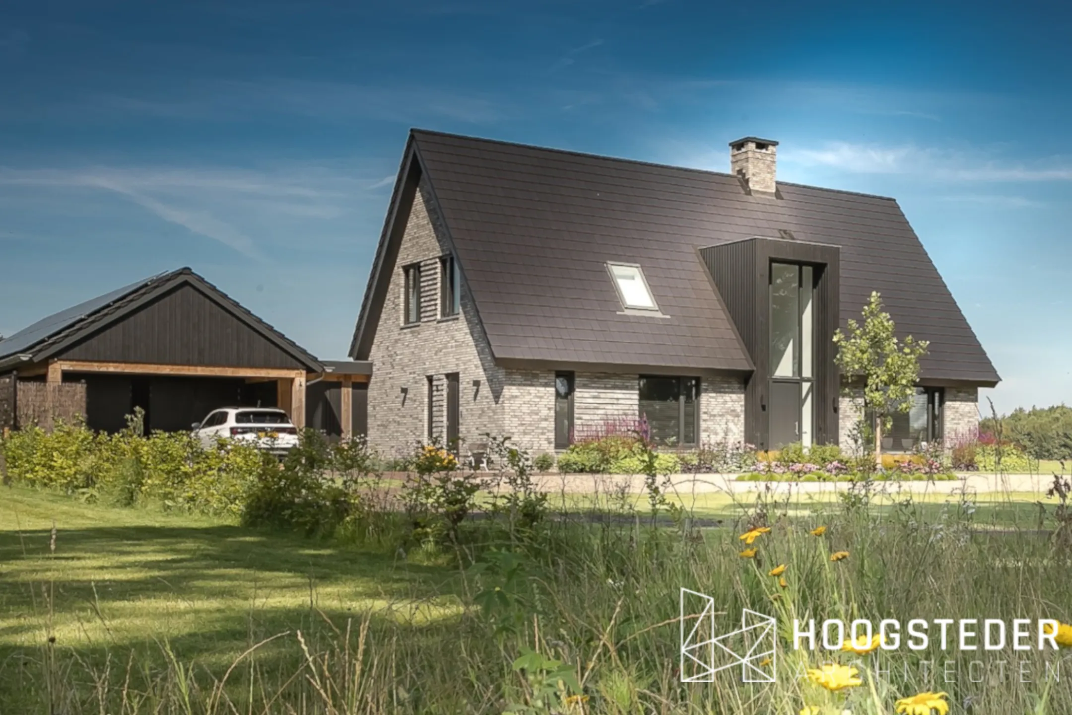 Voorgevel met het houten risaliet rond de entree, en links de carport met donkere houten gevel