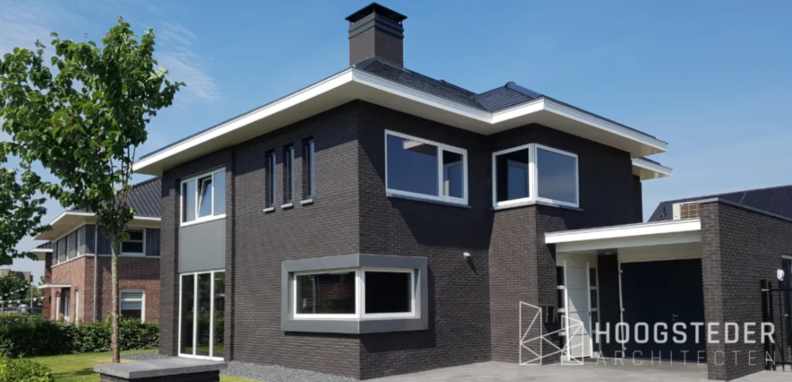 Woning in jaren 30 stijl met donkere baksteen, witte lijsten en een brede erker