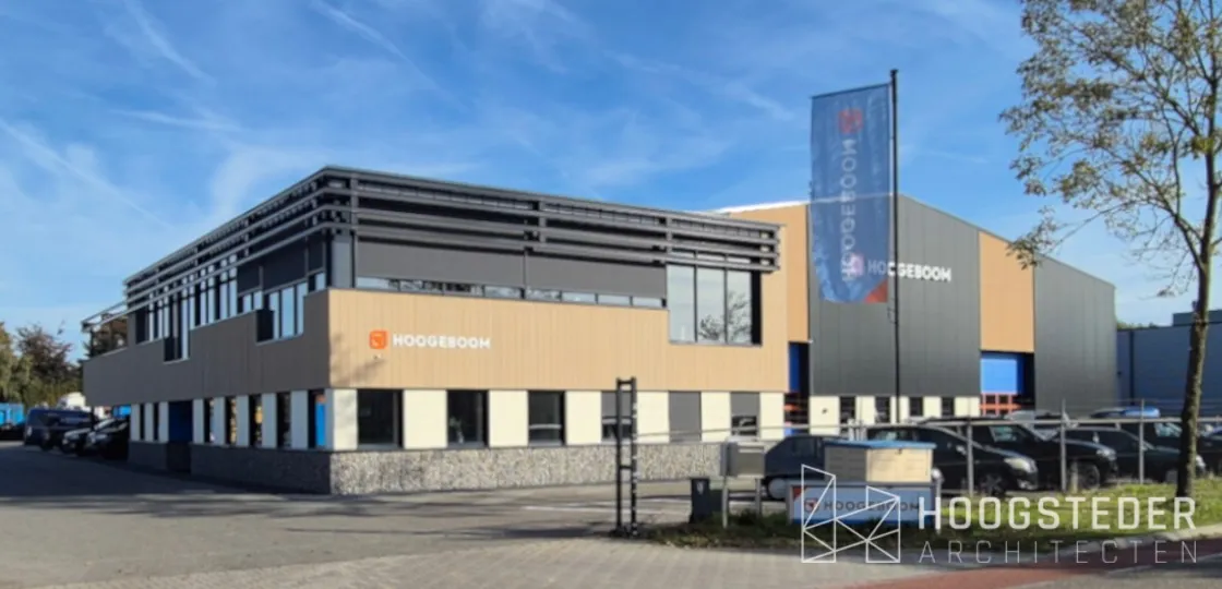 Kantoor van Hoogeboom in Raalte, met een houtkleurige band, de glazen verdieping onder stalen lamellen en grintkorven langs de plint