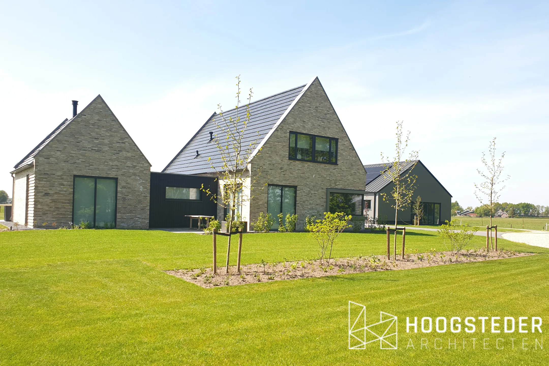De woning vanaf het weiland, met het aparte woonkamervolume links en het bijgebouw rechts