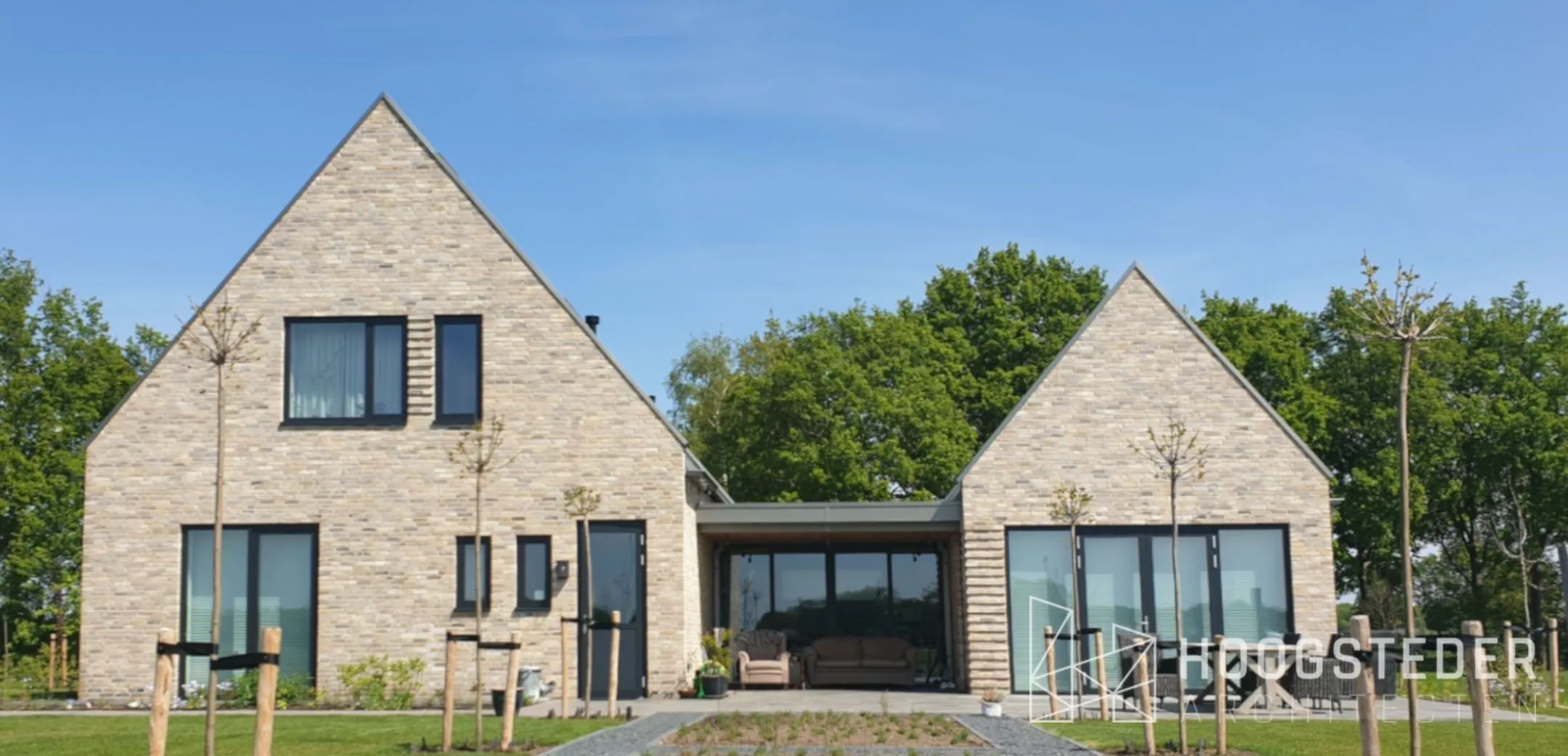 Moderne woning van twee kapvolumes in lichte baksteen met een laag tussenlid van hout en glas