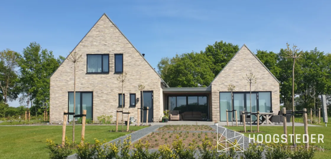 Moderne woning van twee kapvolumes in lichte baksteen met een lage glazen tussenlid