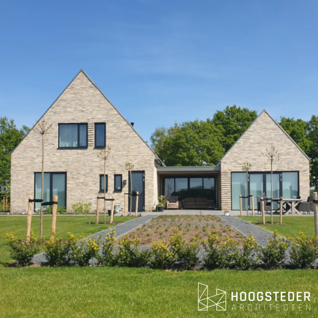 Moderne woning van twee kapvolumes in lichte baksteen met een lage glazen tussenlid