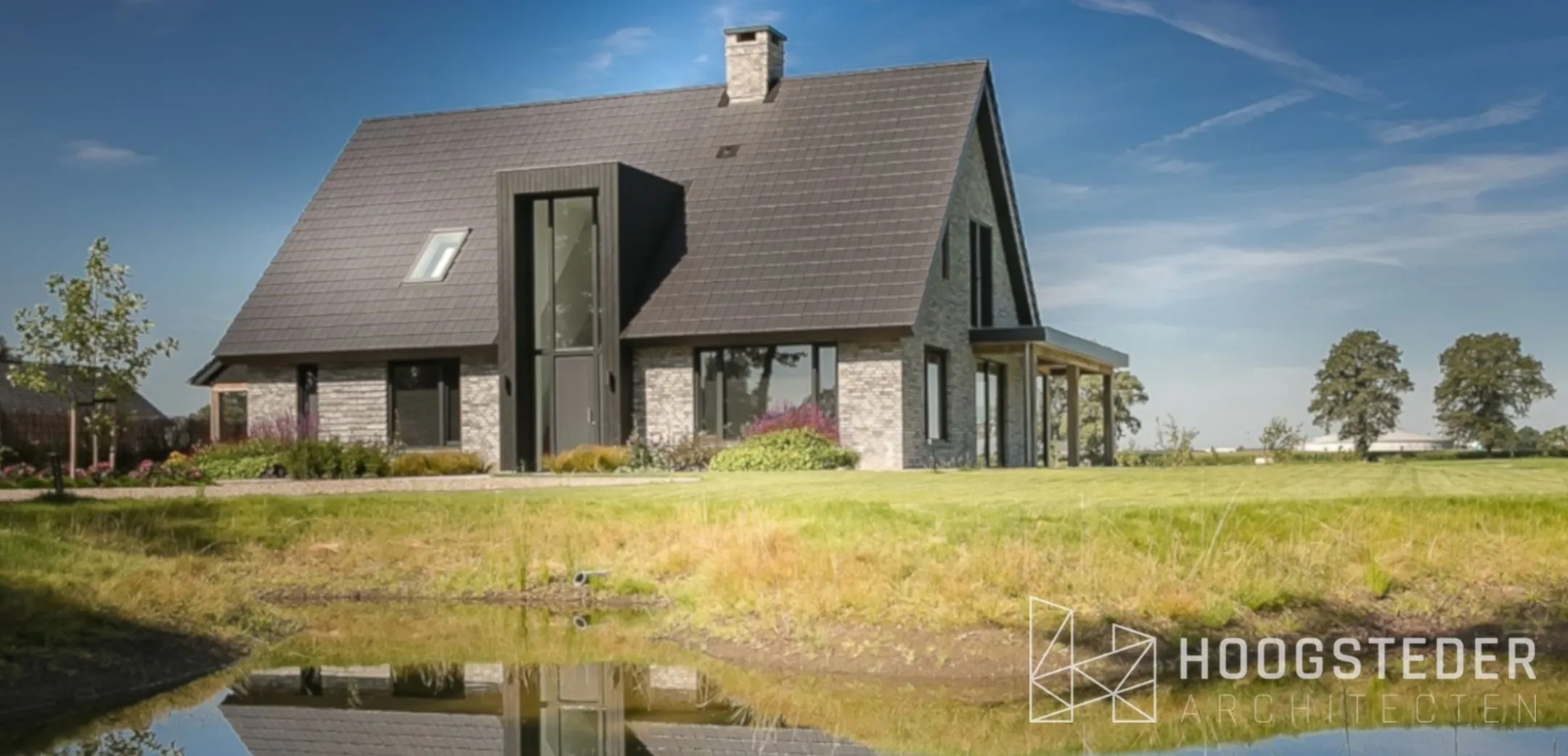 Moderne landelijke woning in het buitengebied van Raalte, gespiegeld in de vijver voor het huis