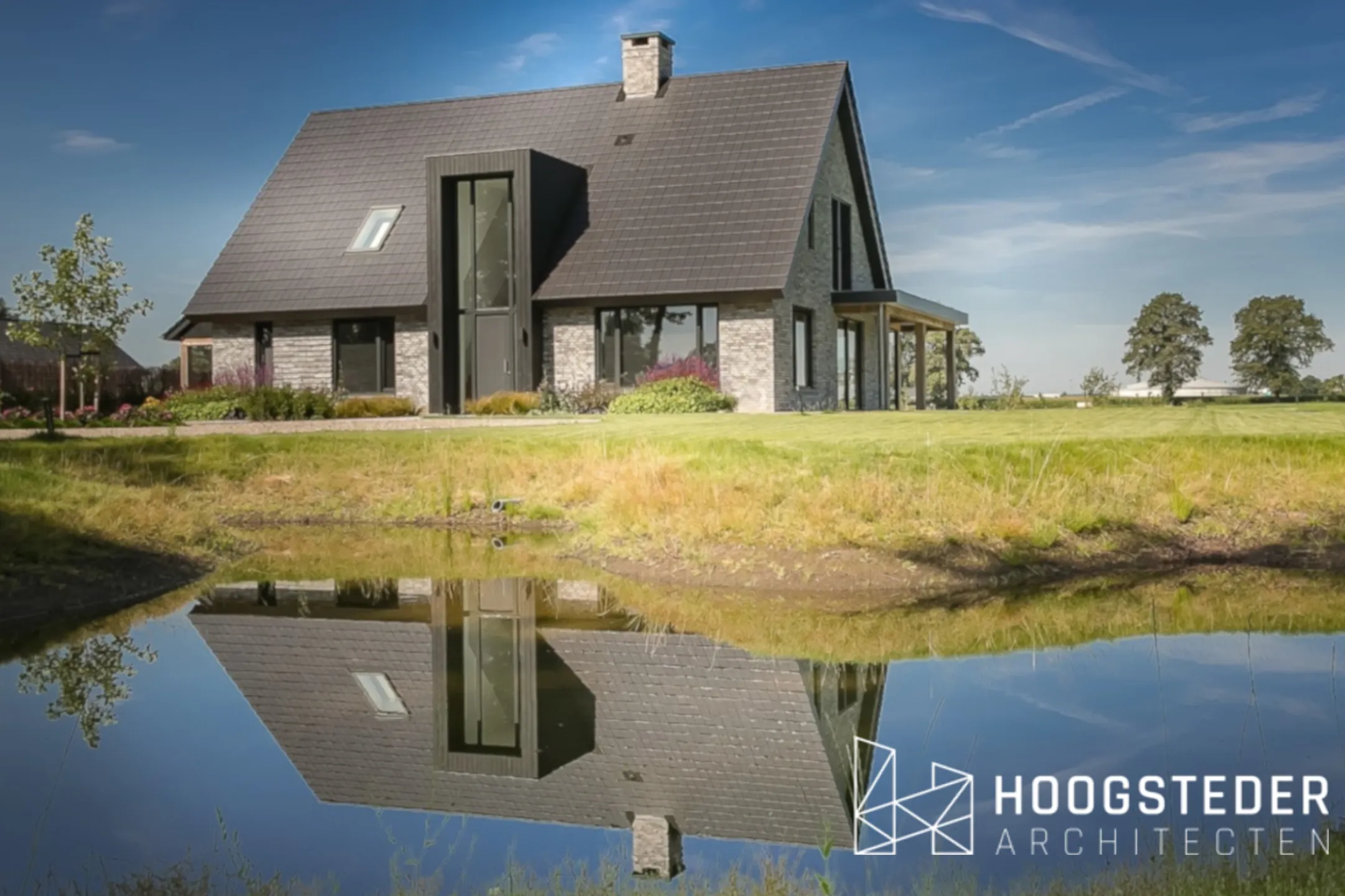 Moderne landelijke woning in het buitengebied van Raalte, gespiegeld in de vijver voor het huis