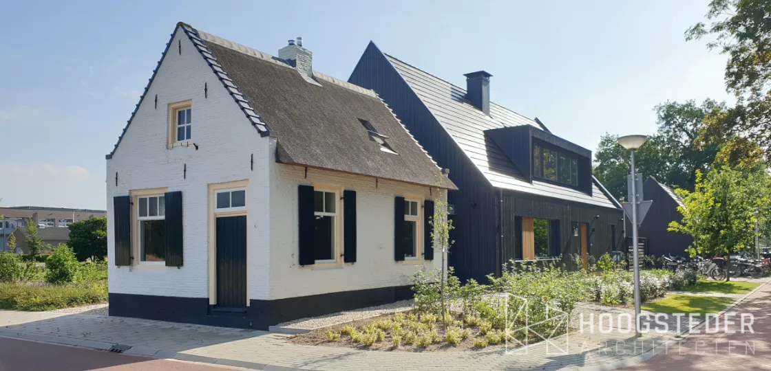 Wit monument met rieten kap naast een nieuwe zwarte schuurwoning met zinken dak