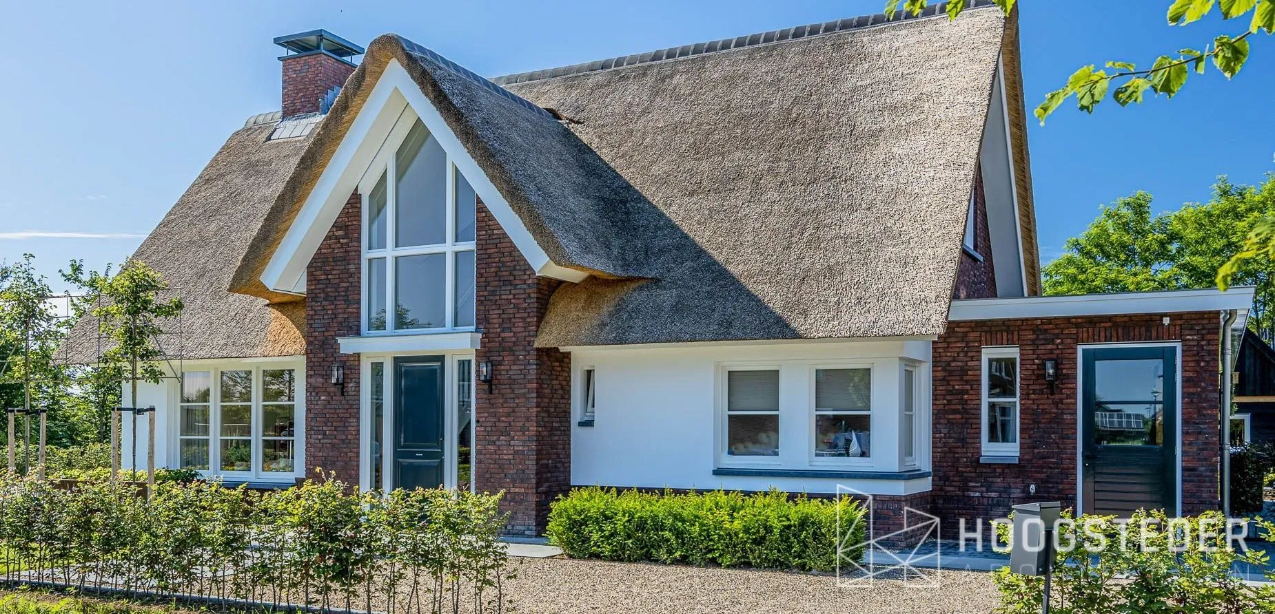 Rietgedekte villa met steile kap, rode baksteen en witte kozijnen