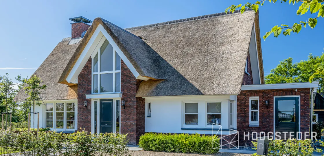 Rietgedekte villa met steile kap, rode baksteen en witte kozijnen