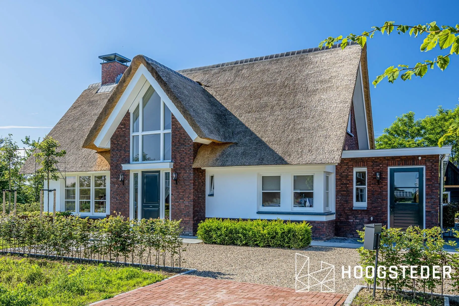 Rietgedekte villa met steile kap, rode baksteen en witte kozijnen