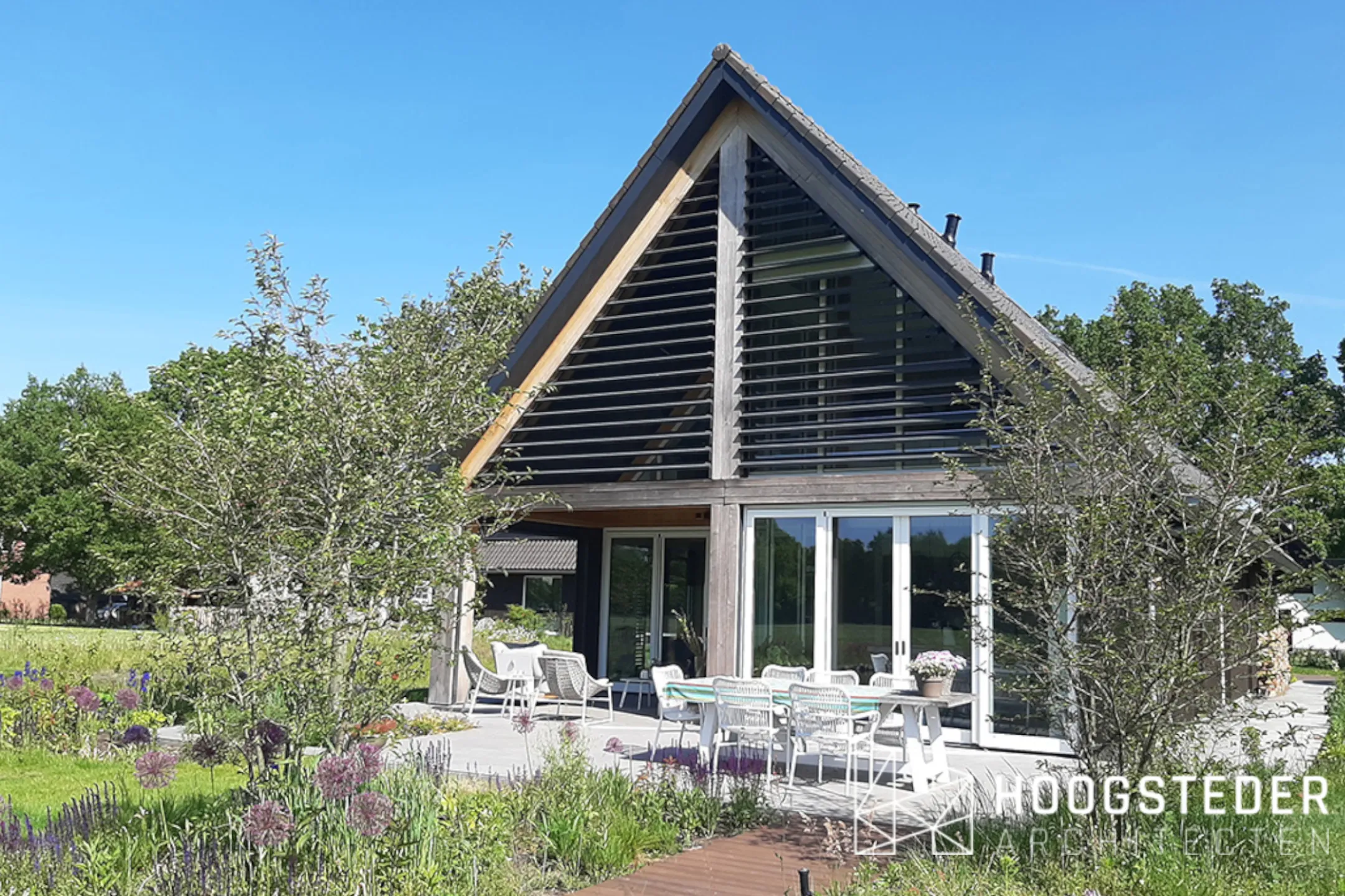 De veranda die doorloopt tot in de kap, met eikenhouten spanten en houten lamellen in de topgevel
