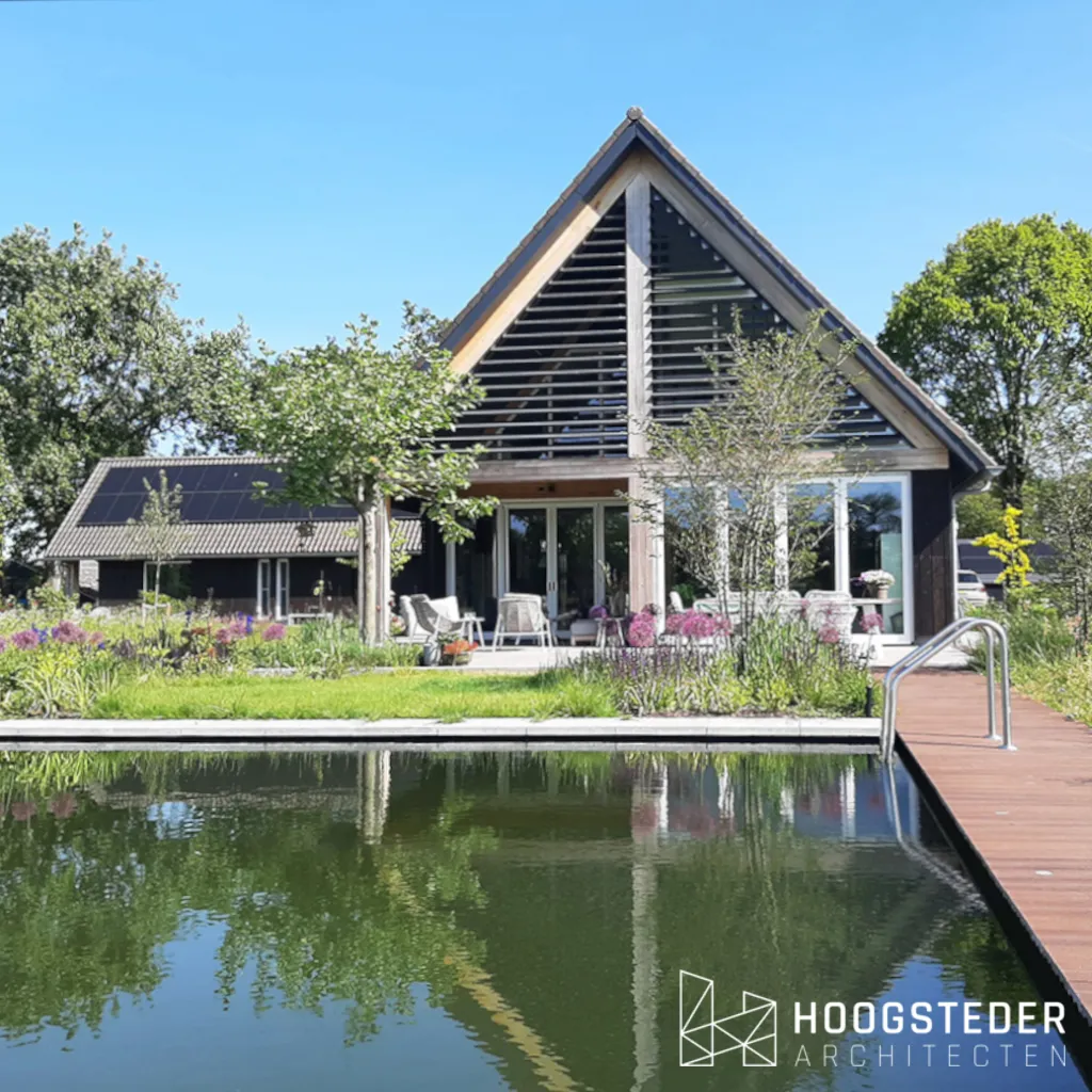 Twee zwarte schuurwoningen op een erf met oude eiken langs de oprit