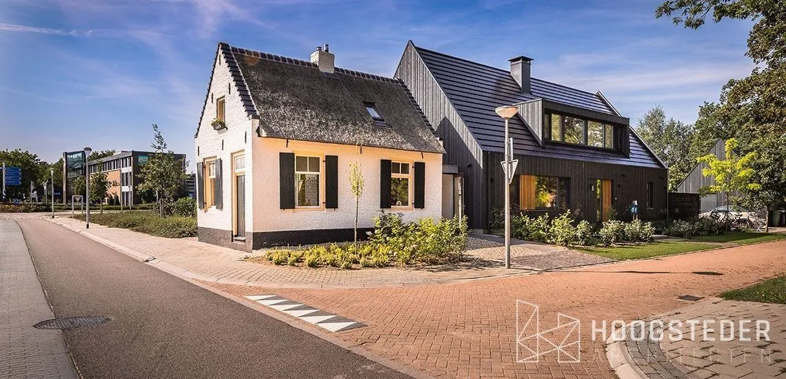 Wit gepleisterd tolhuisje met daarachter een zwarte nieuwbouwwoning met houten gevel