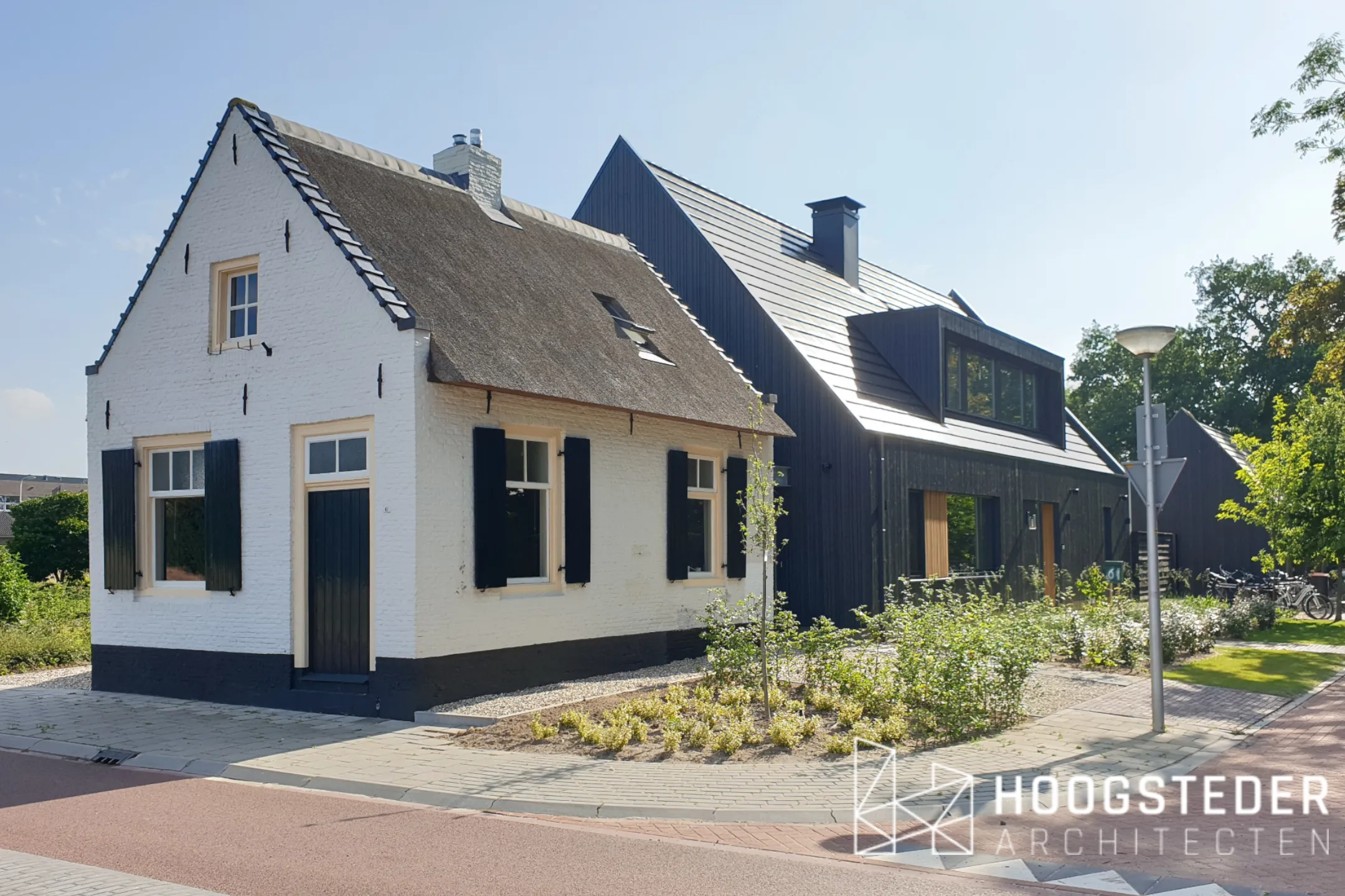 Het witte rietgedekte Tolhuis aan de Zwolsestraat met de donkere nieuwbouwwoning erachter